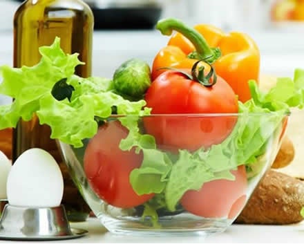 Prato de salada com tomate, alface pimentões e pepino. Azeite, pães e ovos.