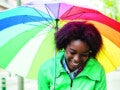 Mulher jovem com guarda-chuva colorido passeando na chuva.
